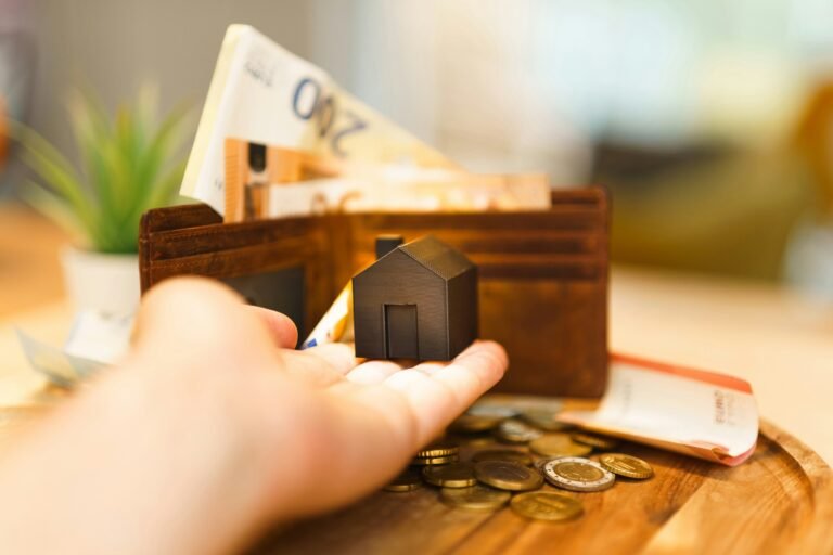 Wooden house on coins representing rising mortgage payments in Canada