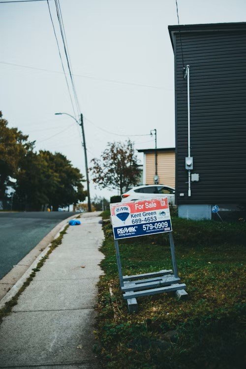 Home for sale sign in front yard with price reduction tag, symbolizing buyer-friendly market